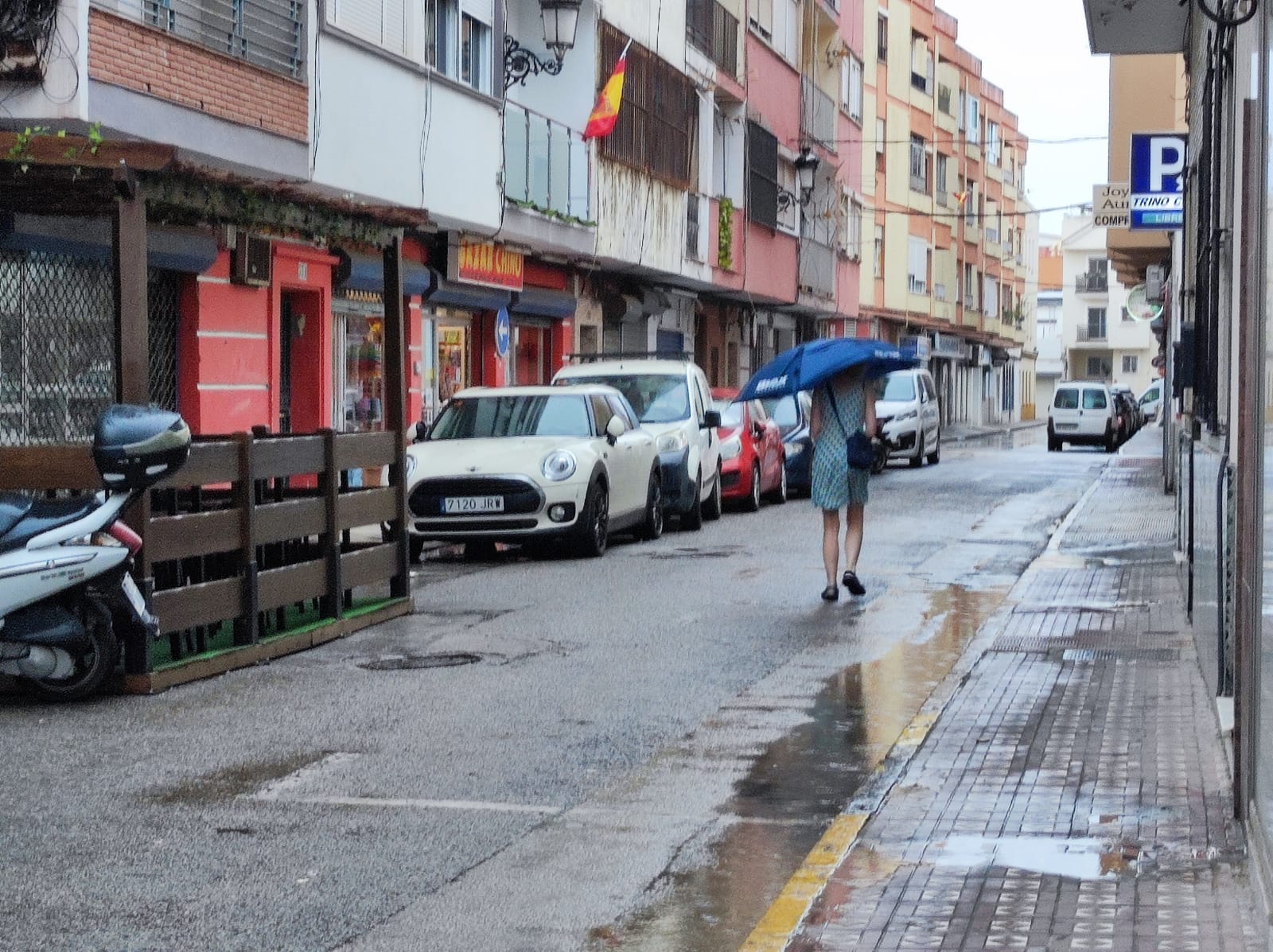 Una mujer se refugia de la lluvia con su paraguas en una calle de La Línea. Foto: S.D.